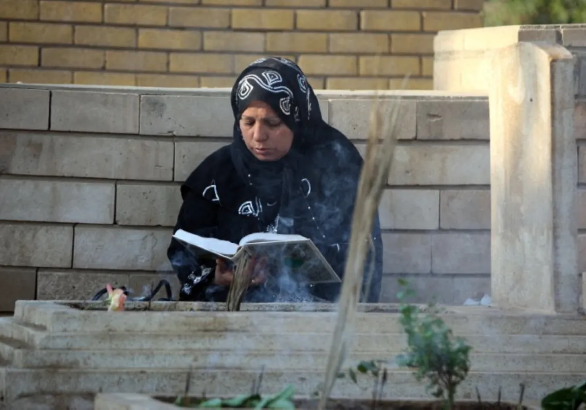 امرأة سنّية عراقية تتلو من القرآن الكريم أثناء زيارتها قبور ذويها في مقبرة الغزالي ببغداد في أول أيام عيد الأضحى، 16 نوفمبر 2010
