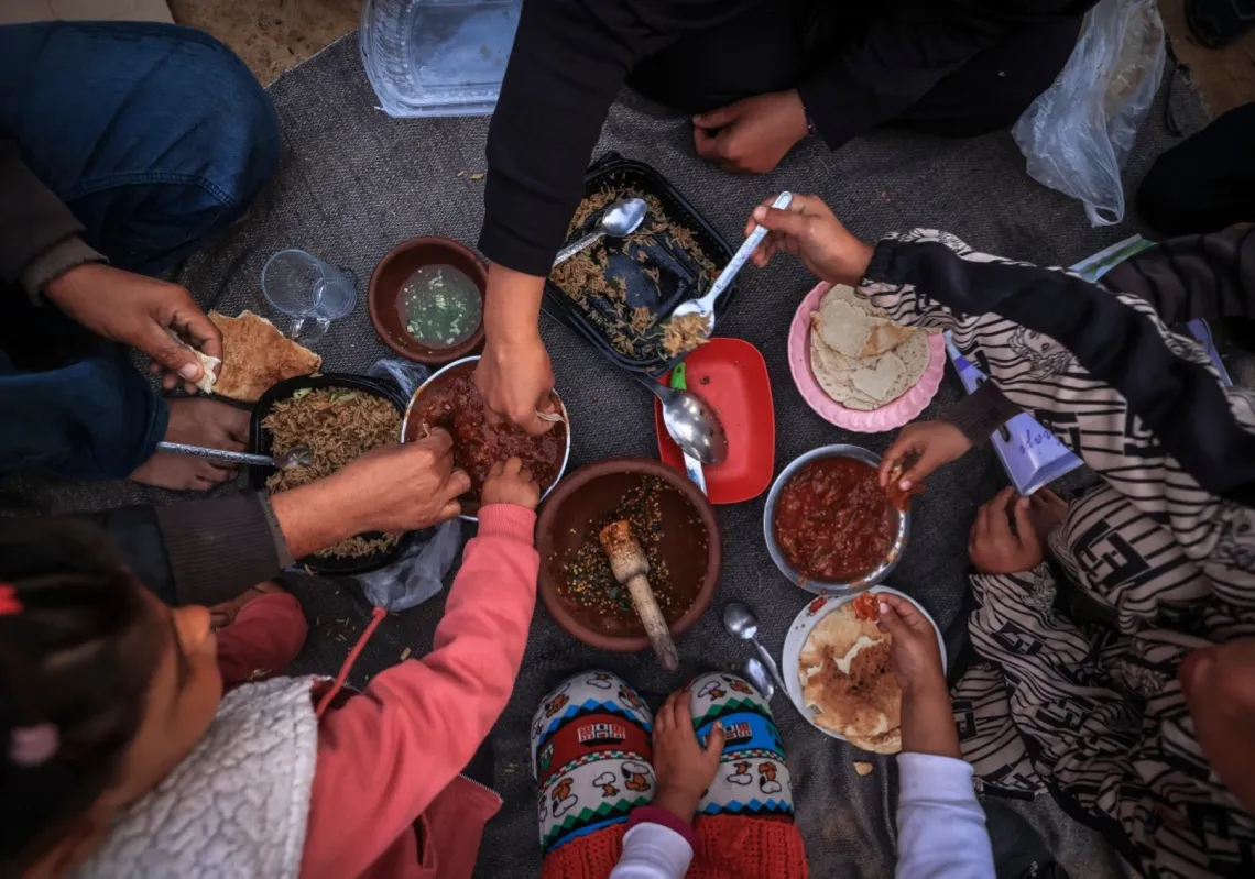 The displaced Palestinian Abu Mustafa family sits together as they break the dawn-to-dusk Ramadan fast during Iftar in the Nuseirat refugee camp in the central Gaza Strip on 26 February 2026.