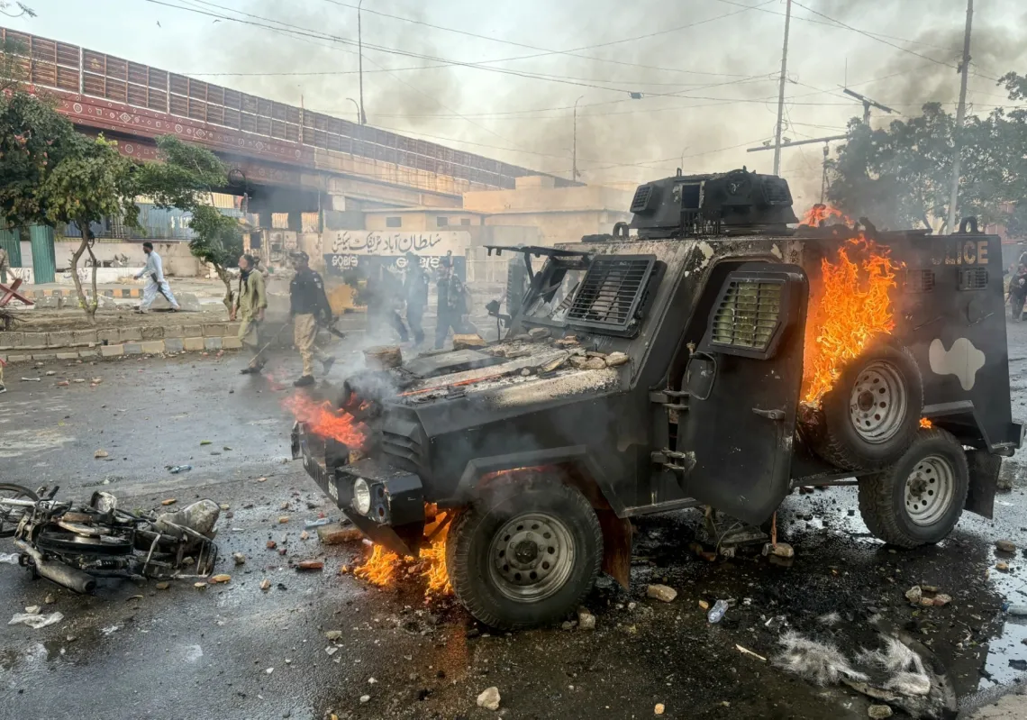 Police walk past a burning armoured vehicle set on fire by protestors outside the US consulate in Karachi, Pakistan on March 1, 2026 after the killing of Iran's Supreme Leader.