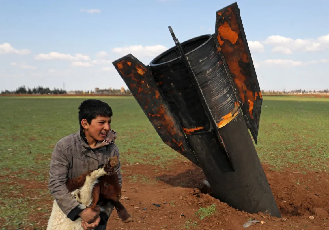 A boy plays with his sheep next to an unexploded missile that landed in an open field on the outskirts of Qamishli, eastern Syria, on 5 March 2026.