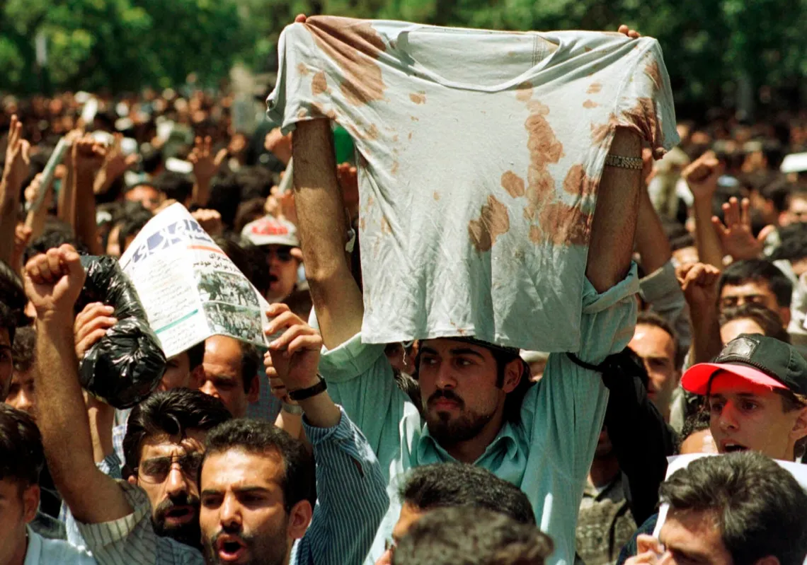 طالب يرفع قميصا ملطخا بالدماء لصديق أُصيب خلال مواجهات بين الشرطة ومتظاهرين طلاب في طهران، 12 يوليو 1999