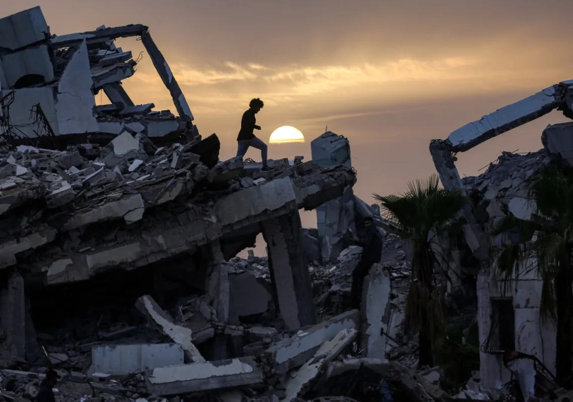 شاب يسير بين أنقاض مبنى مدمر في حي الزهراء، جنوب غرب النصيرات وسط قطاع غزة، في 6 فبراير 2026