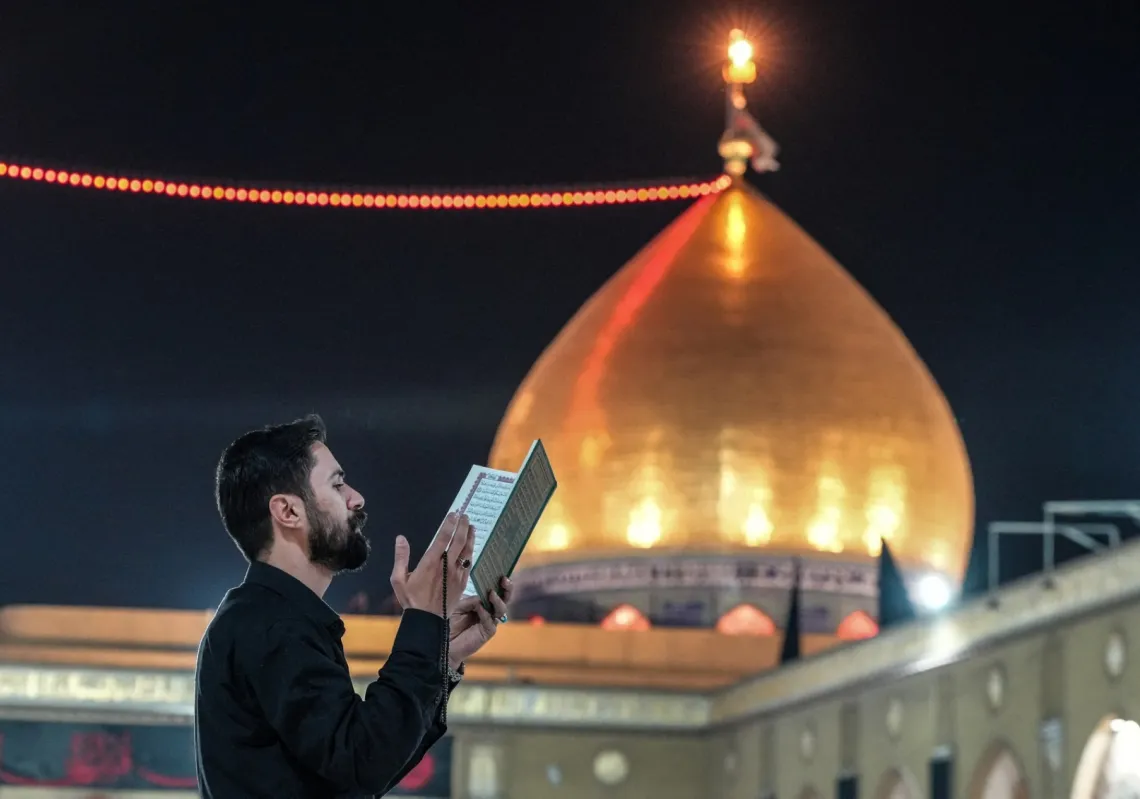 معتكف شيعي يتلو القرآن في مسجد الكوفة جنوب بغداد، 12 مارس 2026