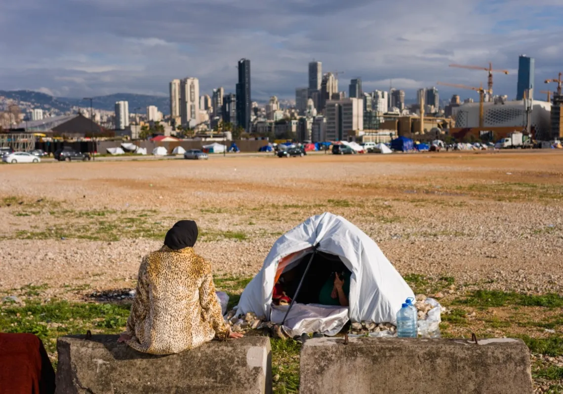 A displaced woman sits next her tent in an unofficial camp, erected along Beirut’s seafront area on 22 March 2026.