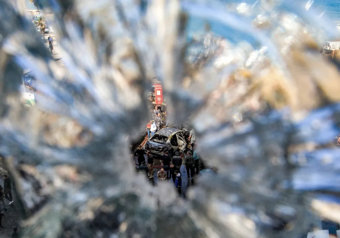 عناصر من الدفاع المدني يتجمعون حول مركبة مدمرة جراء قصف إسرائيلي في مدينة صيدا، 18 مارس 2026