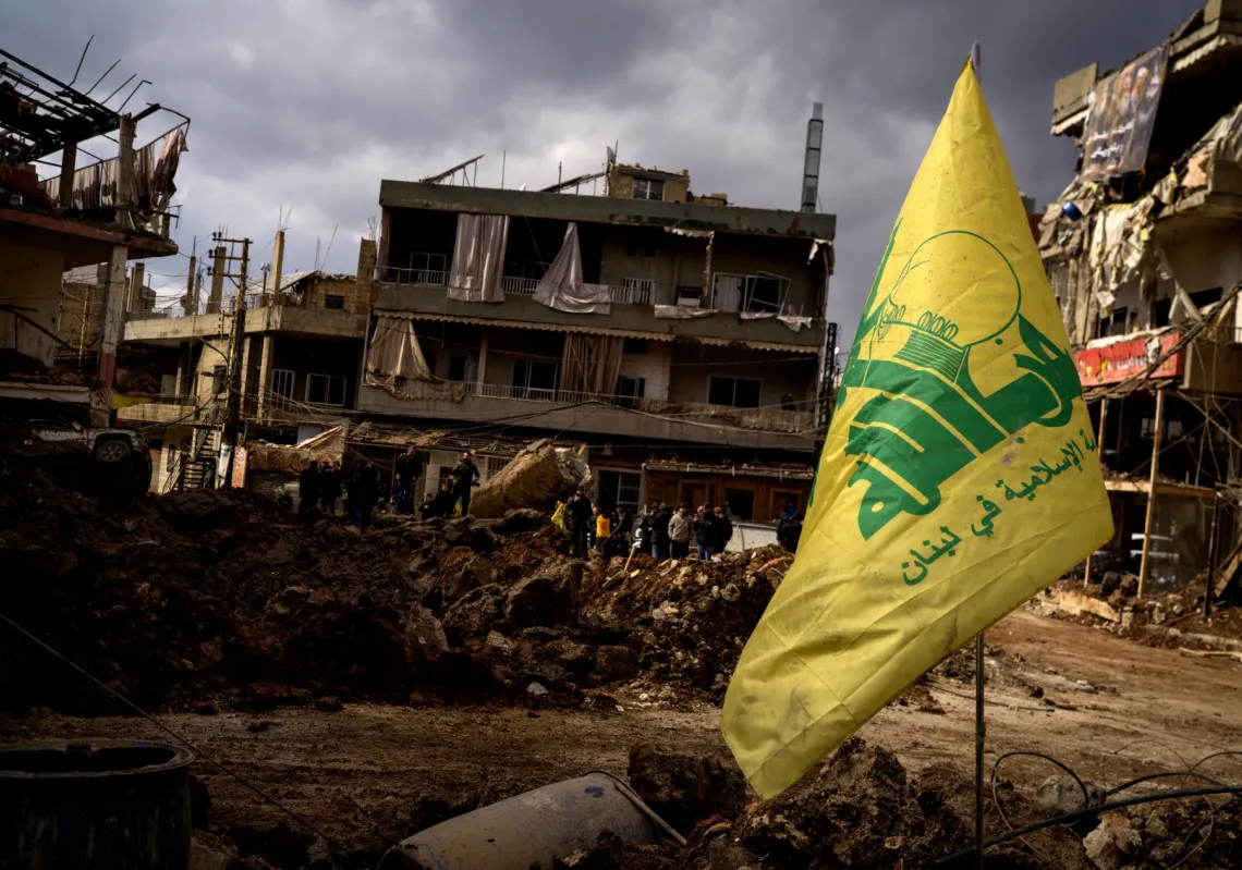 علم "حزب الله" أمام مبانٍ مدمرة جراء غارة جوية سابقة في 7 مارس 2026 في مدينة النبي شيت اللبنانية