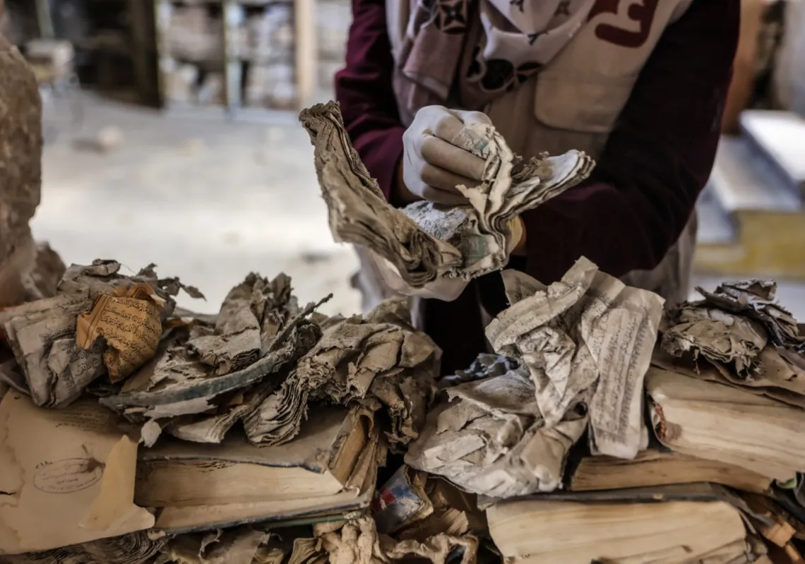 متطوع فلسطيني يعمل على إنقاذ وترميم كتب ومخطوطات متضررة داخل مكتبة الجامع العمري الكبير في مدينة غزة، 26 فبراير 2026