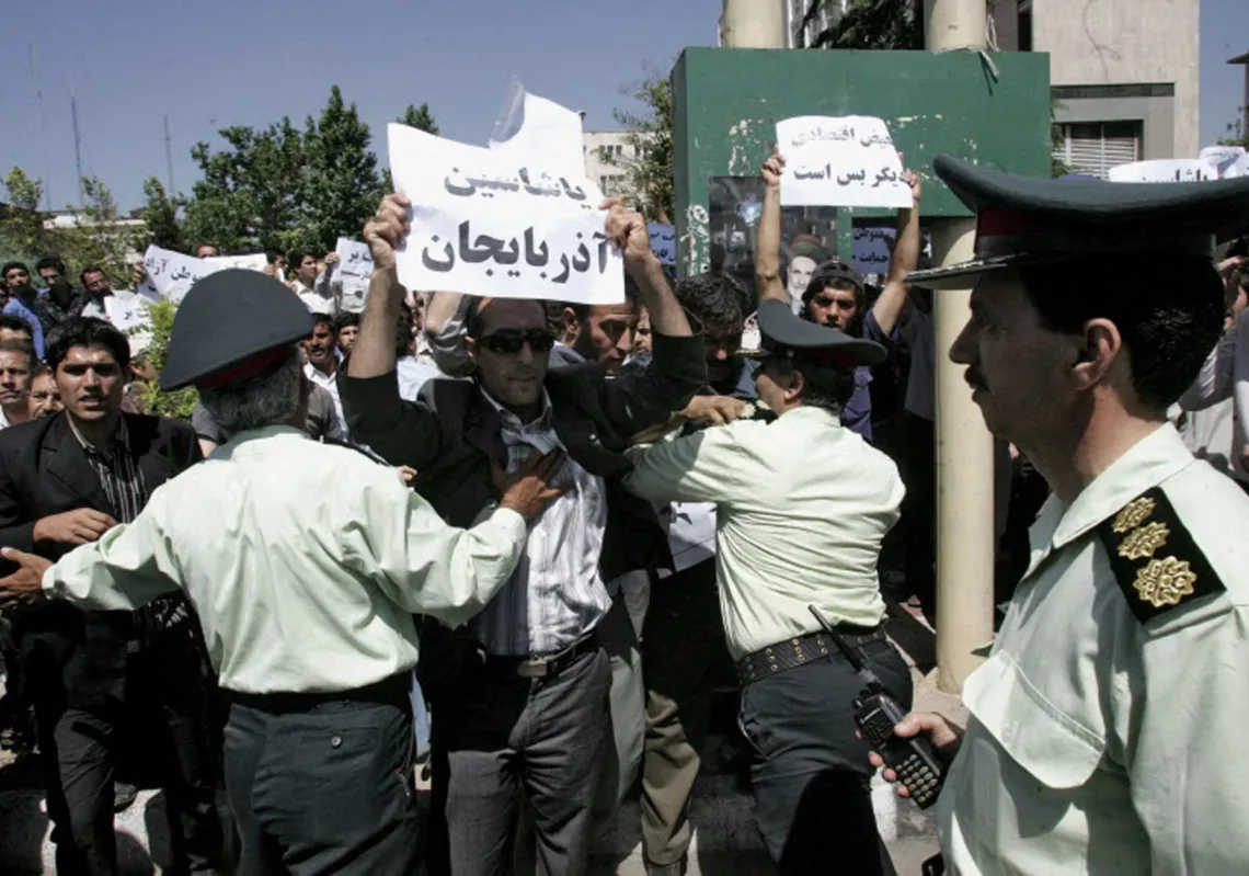 عناصر الشرطة الايرانية يحاولون تفريق متظاهرون اذريون يرفعون لافتة كتب عليها "تحيا أذربيجان" خارج وزارة الثقافة الايرانية في طهران في 28 مايو 2006 