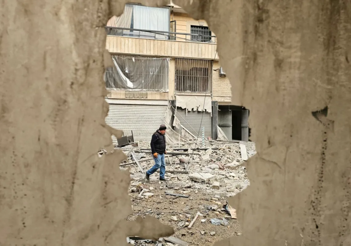 رجل يسير في شارع تتناثر فيه مخلفات البناء في موقع غارة جوية إسرائيلية استهدفت حيًا في الضاحية الجنوبية لبيروت، 25 مارس 2026