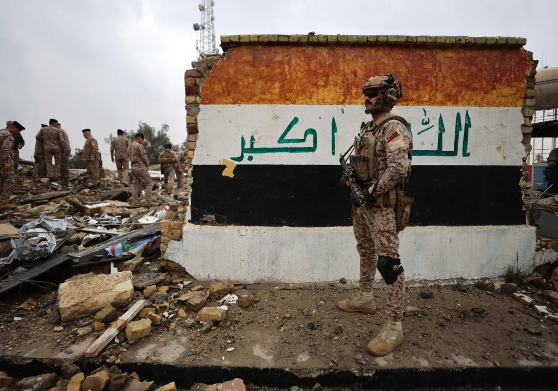 جندي عراقي يقف أمام مركز صحي مدمر تعرض للقصف، في منطقة الرحبانية 26 مارس 2026