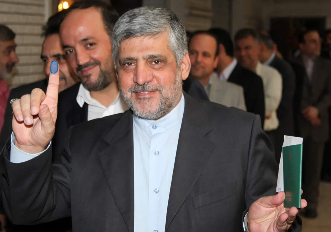  السفير الإيراني محمد رضا شيباني، يظهر إصبعه الملطخ بالحبر أثناء إدلائه بصوته في الجولة الأولى من الانتخابات الرئاسية الإيرانية في السفارة الإيرانية بالعاصمة السورية دمشق، في 14 يونيو 2013 