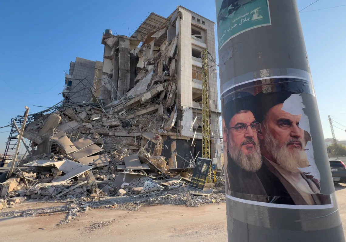 صورتان لأمين عام حزب الله السابق حسن نصر الله، ومؤسس الثورة الإيرانية الراحل، آية الله الخميني، أمام مبنى مدمر كان يضم فرعًا لمؤسسة القرض الحسن، في الضاحية الجنوبية لبيروت، لبنان، 10 مارس 2026