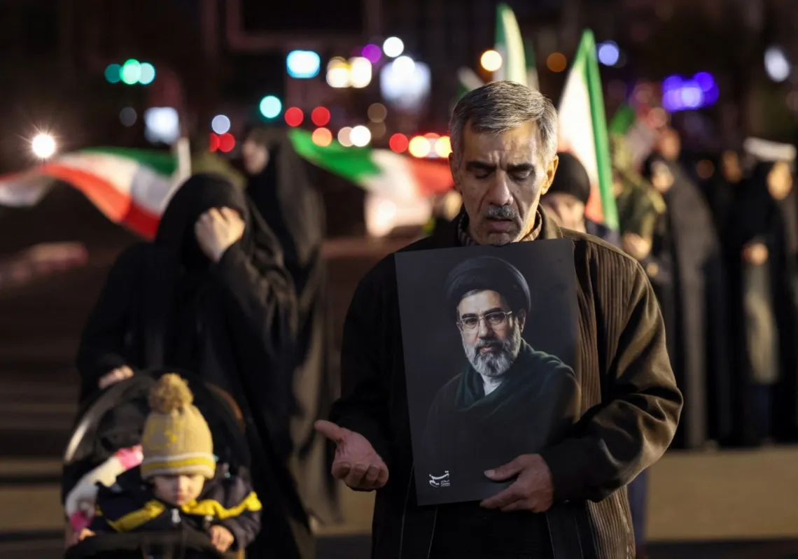 A man reacts as he holds a portrait of Iran's supreme leader Mojtaba Khamenei as people march in support of the Iranian armed forces in central Tehran on 25 March 2026.
