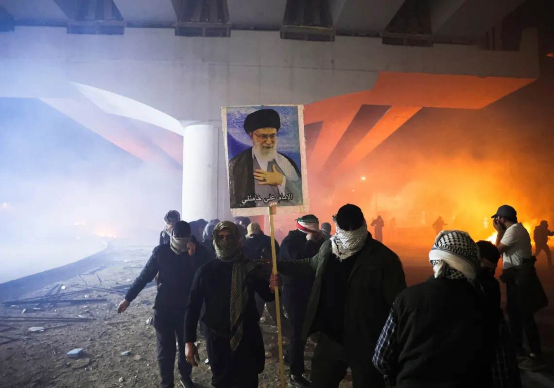 متظاهر يحمل صورة المرشد الإيراني الراحل علي خامنئي، بينما يحاول أنصار الجماعات الشيعية العراقية المسلحة التوجه نحو السفارة الأميركية في المنطقة الخضراء ببغداد، العراق، 1 مارس 2026