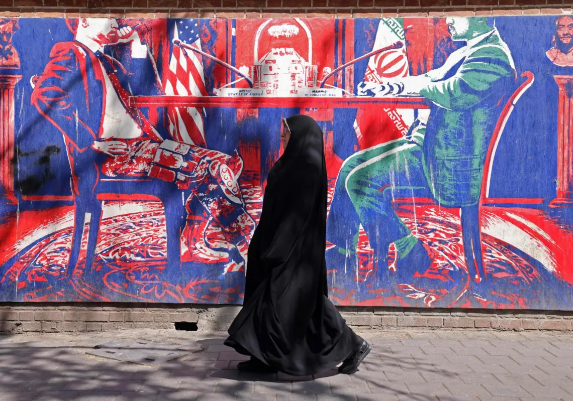 امرأة أمام جدارية تحاكي المحادثات بين إيران وأميركا قرب السفارة الأميركية السابقة في طهران، في 11 أبريل 2026