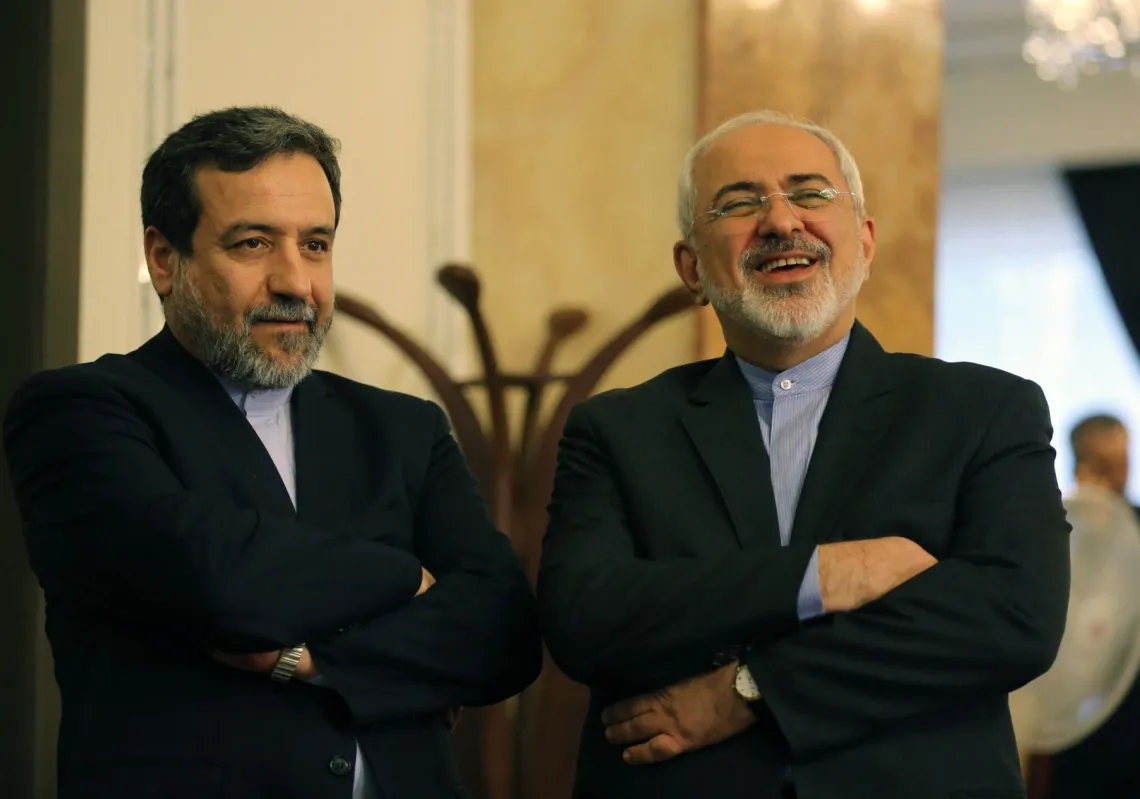 Iranian Foreign Minister Javad Zarif (R) and Deputy Foreign Minister and chief nuclear negotiator Abbas Araghchi react as they listen to President Hassan Rouhani (unseen) speaking during a press conference in Tehran on 3 April 2015