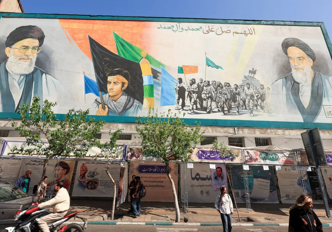 مارة يسيرون بجانب جدارية تُظهر روح الله الخميني وعلي خامنئي في طهران، 16 أبريل 2026