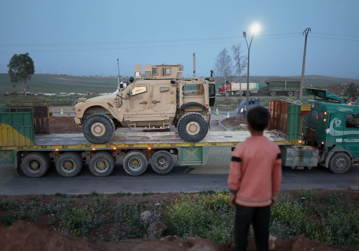 فتى يتابع تحرك عربة عسكرية أميركية تنسحب من قاعدة قسرك شمال شرقي سوريا باتجاه الاردن في 16 أبريل 2026