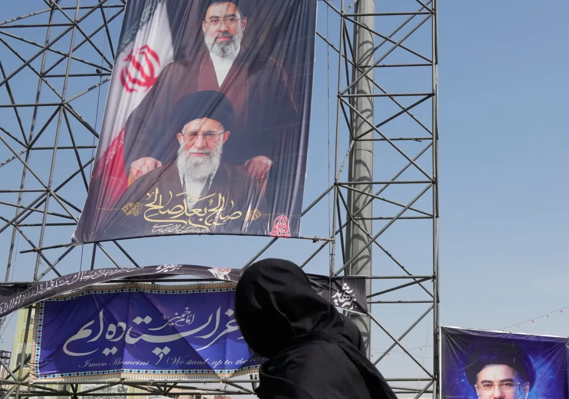 امرأة في طهران تمر أمام لوحات تُظهر مجتبى خامنئي ووالده علي خامنئي الذي قتل في ضربات أميركية-إسرائيلية، 16 أبريل 2026