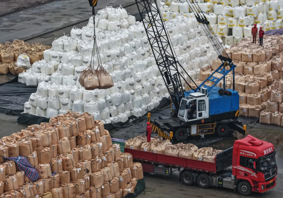 عمال يحمّلون الكبريت في ساحة تخزين على رصيف بحري في نانجينغ، مقاطعة جيانغسو شرق الصين، 14 أبريل 2026