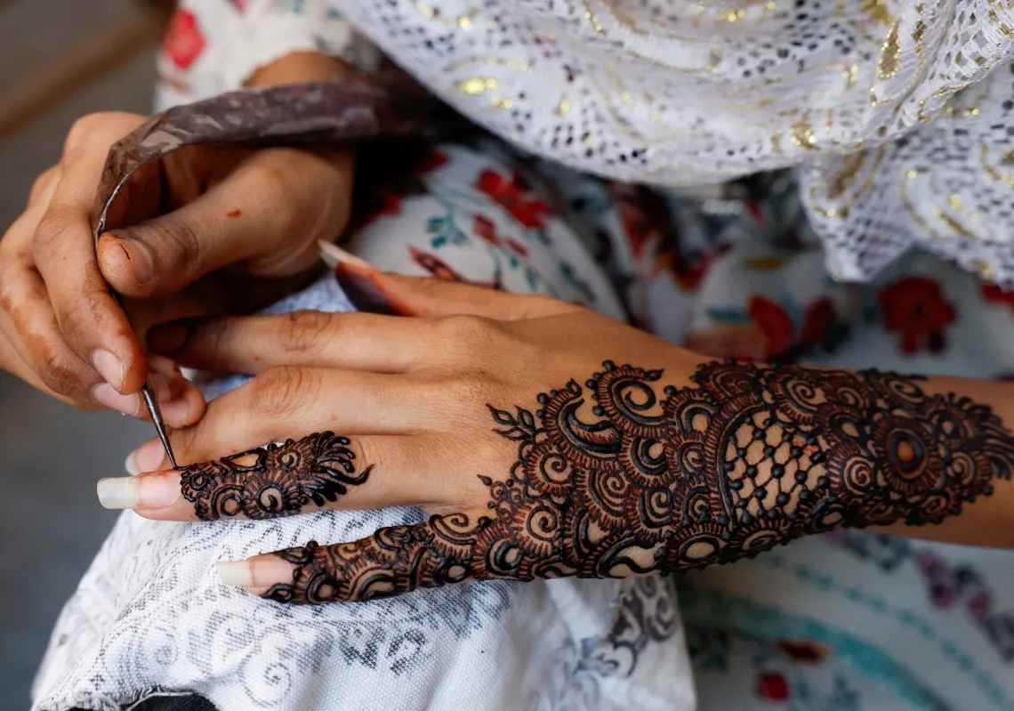 فتاة ترسم نقوش الحناء على يديها
