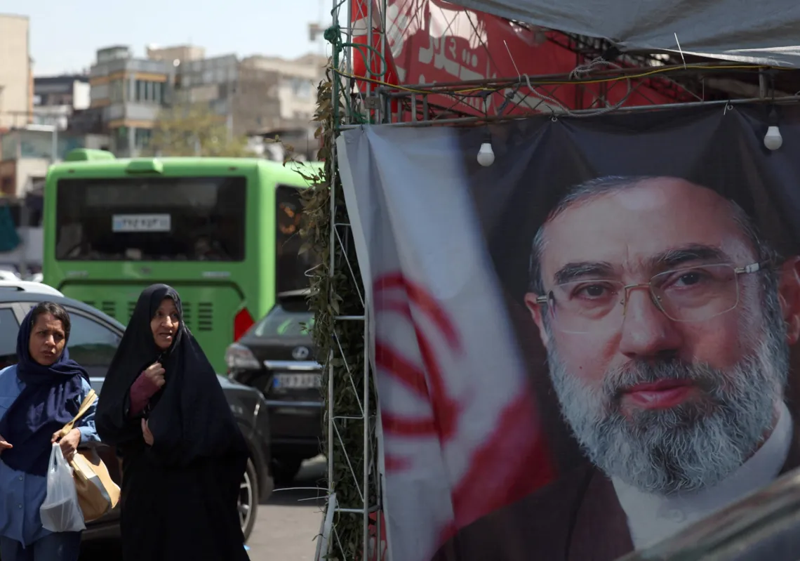 نساء إيرانيات يمررن بجانب لافتة تُظهر "المرشد الأعلى" مجتبى خامنئي في طهران، وسط استمرار القيود على الملاحة في مضيق هرمز، 16 أبريل 2026