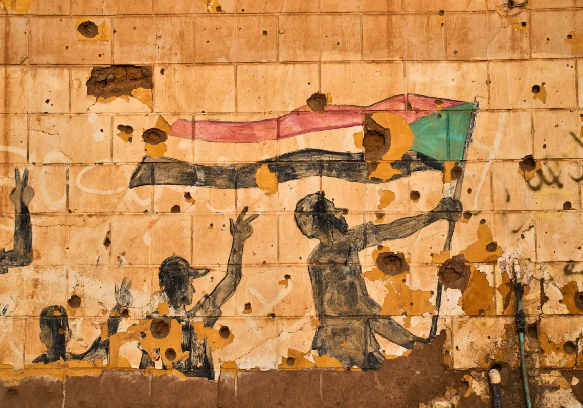 جدارية لأشخاص يحملون العلم السوداني على حائط متضرر من الرصاص والشظايا في أم درمان، على مشارف الخرطوم، السودان، 23 أبريل 2026