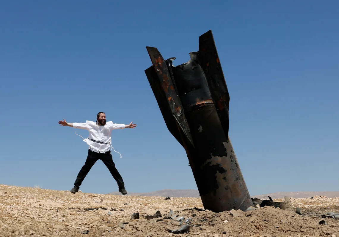 
يهودي إسرائيلي متشدد يتفاعل بالقرب من جزء من صاروخ مغرس في الأرض، في أعقاب ضربات إيرانية، في وسط الضفة الغربية المحتلة، في 8 يونيو 2026