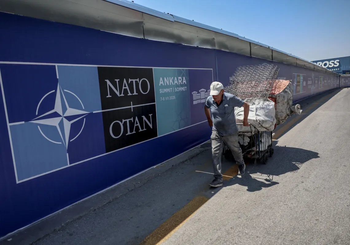 A paper collector pulls his handcart past billboards lining the boulevard along the protocol route ahead of the NATO Summit in Ankara on 2 July 2026.