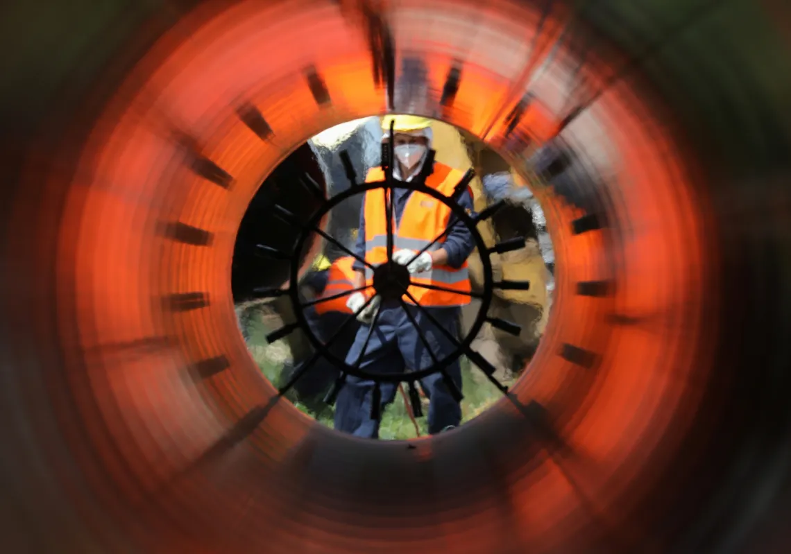 Workers are seen through a pipe at a construction site on the extension of Russia's TurkStream gas pipeline.