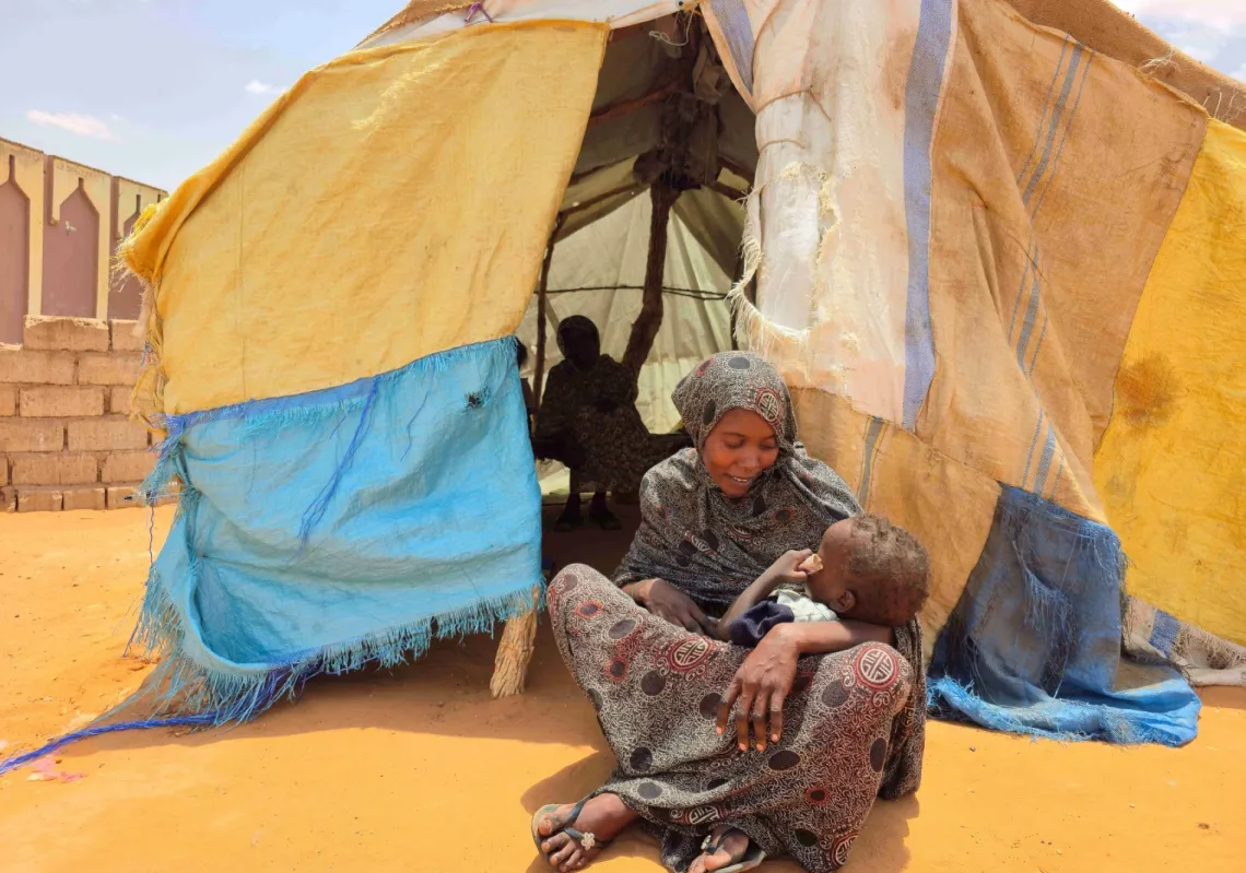 A Sudanese woman sits with her child at the Al-Rahmaniya camp for displaced persons, near the city of El Obeid in the South Kordofan region of Sudan, on June 25, 2026.