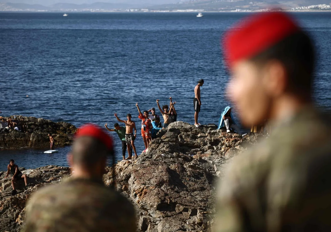 Members of the Spanish Army's 'Regulares' infantry forces watch a group of migrants near the border post of the Spanish enclave of Ceuta on August 2, 2026.