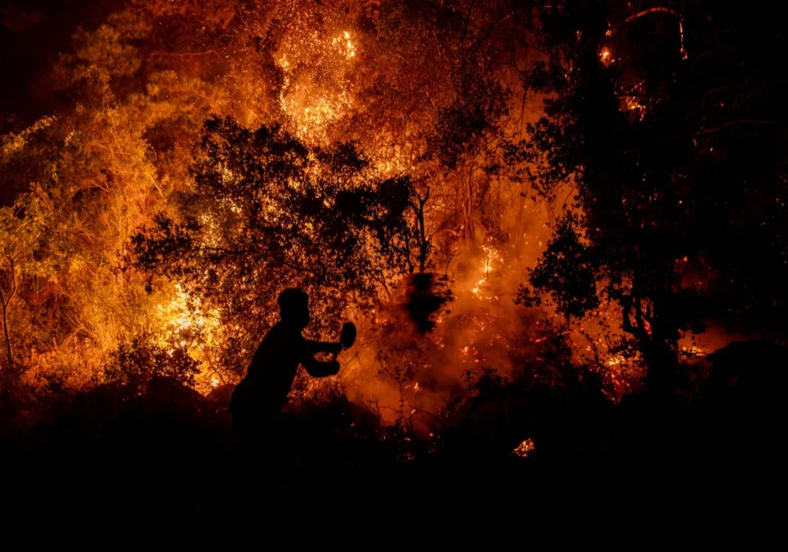 متطوع يستخدم مجرفة أثناء مكافحة حريق هائل في منطقة سيديكيمر بمحافظة موغلا التركية