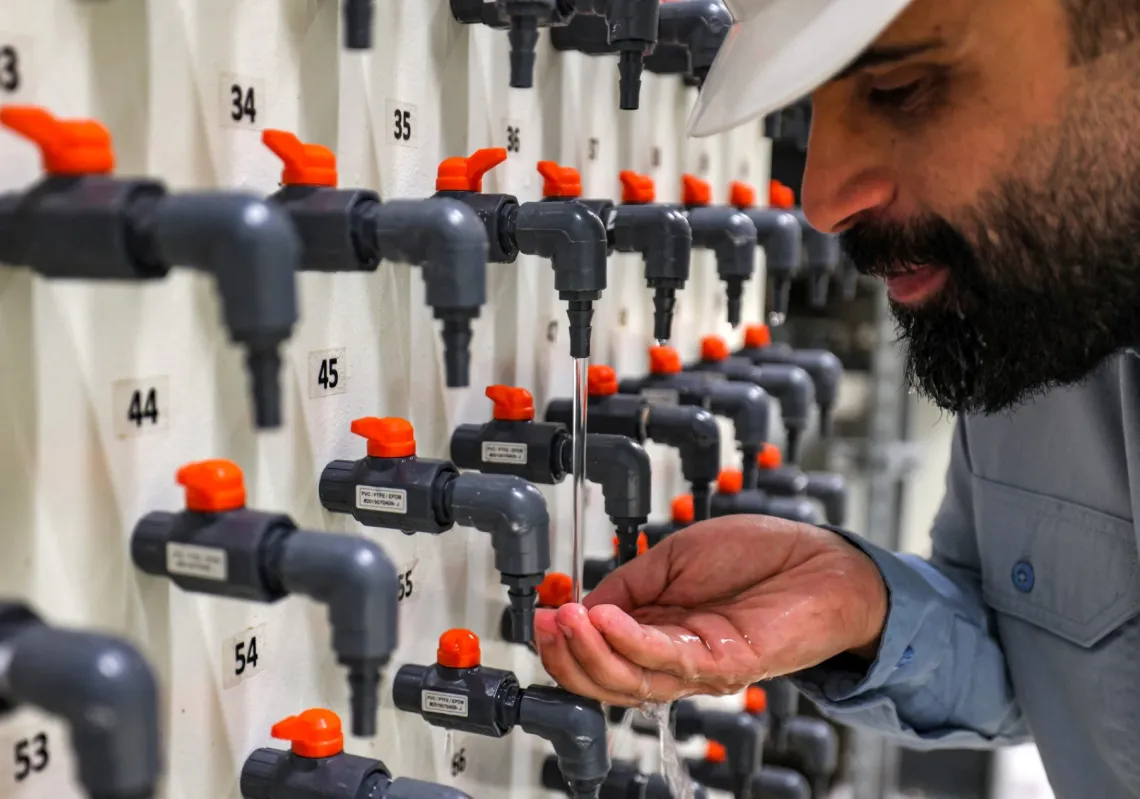 The general manager of the Ras al-Khair water desalination plant inspects drinking water from a tap at the facility in eastern Saudi Arabia on 30 March 2023.