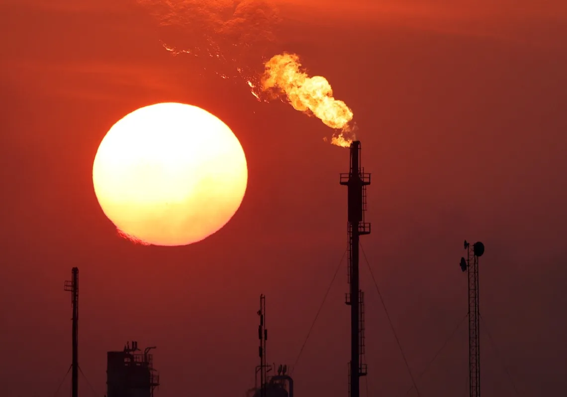 The sun sets behind burning gas flares at the Daura Oil Refinery Complex in Baghdad, 22 December 2024