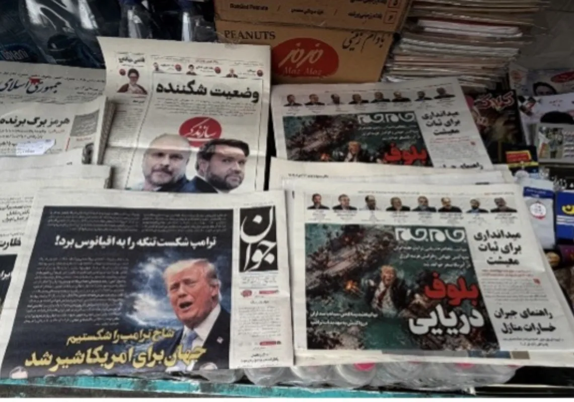 في أحد أكشاك بيع الصحف بطهران، 13 أبريل 2026، الصفحة الأولى من صحيفة "جوان" (إلى اليسار) والصفحة الأولى من صحيفة "جام جام" التي تتضمن رسماً كاريكاتورياً للرئيس الأمريكي دونالد ترامب وهو يغرق في مضيق هرمز، مصحوباً بعنوان "خديعة بحرية