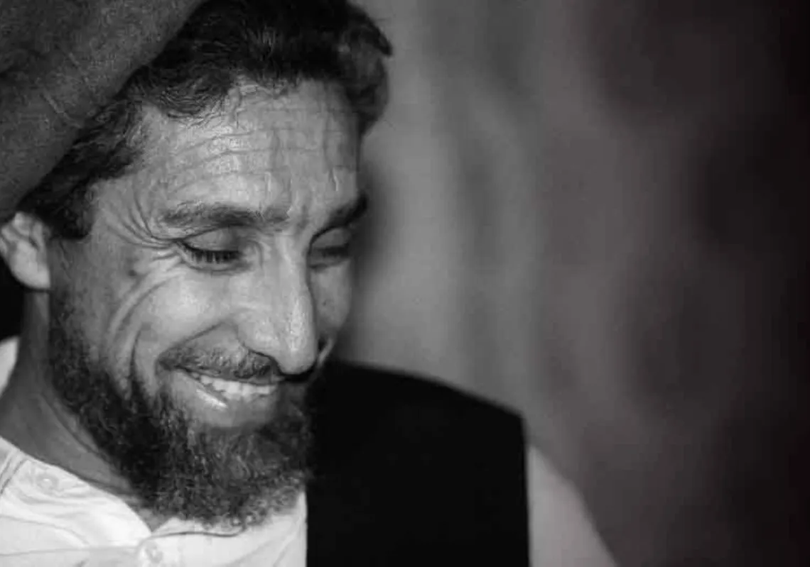 أحمد شاه مسعود يبتسم خلال مقابلة صحفية في مقرّه بأفغانستان، في صورة التُقطت في 28 يونيو 2001
