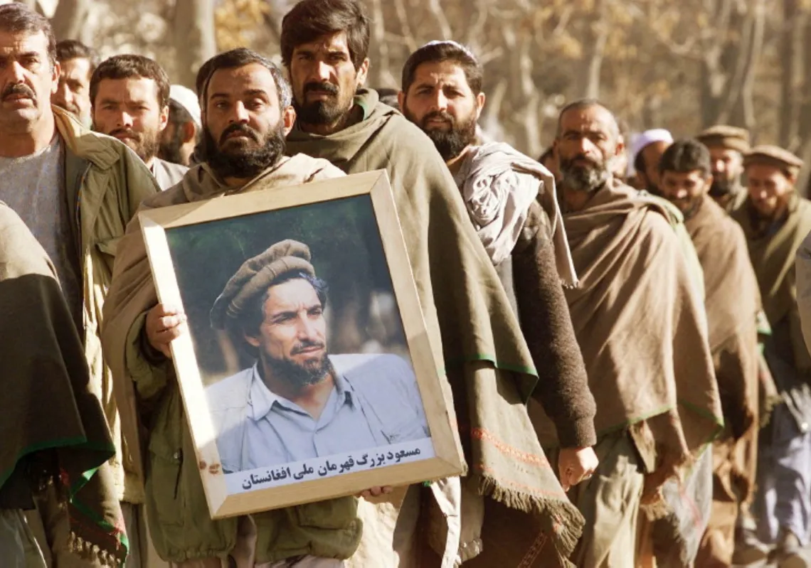 أفغاني يحمل صورة الراحل أحمد شاه مسعود بينما يسير آخرون خلفه متجهين إلى مسجد في كابول، في 5 ديسمبر 2001