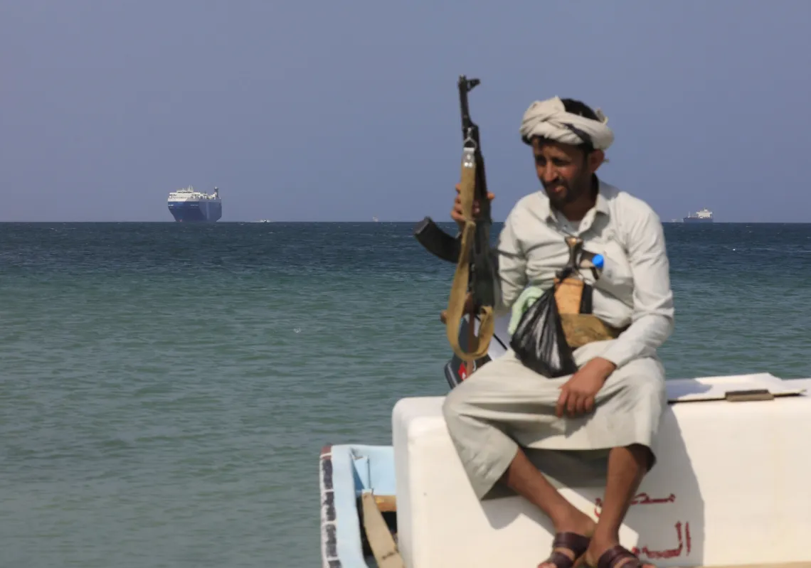 مسلح يمني يجلس على متن قارب أمام سفينة الشحن "غالاكسي ليدر"، التي استولى عليها الحوثيون قبالة شاطئ ميناء الصليف على البحر الأحمر في محافظة الحديدة، 5 ديسمبر الماضي