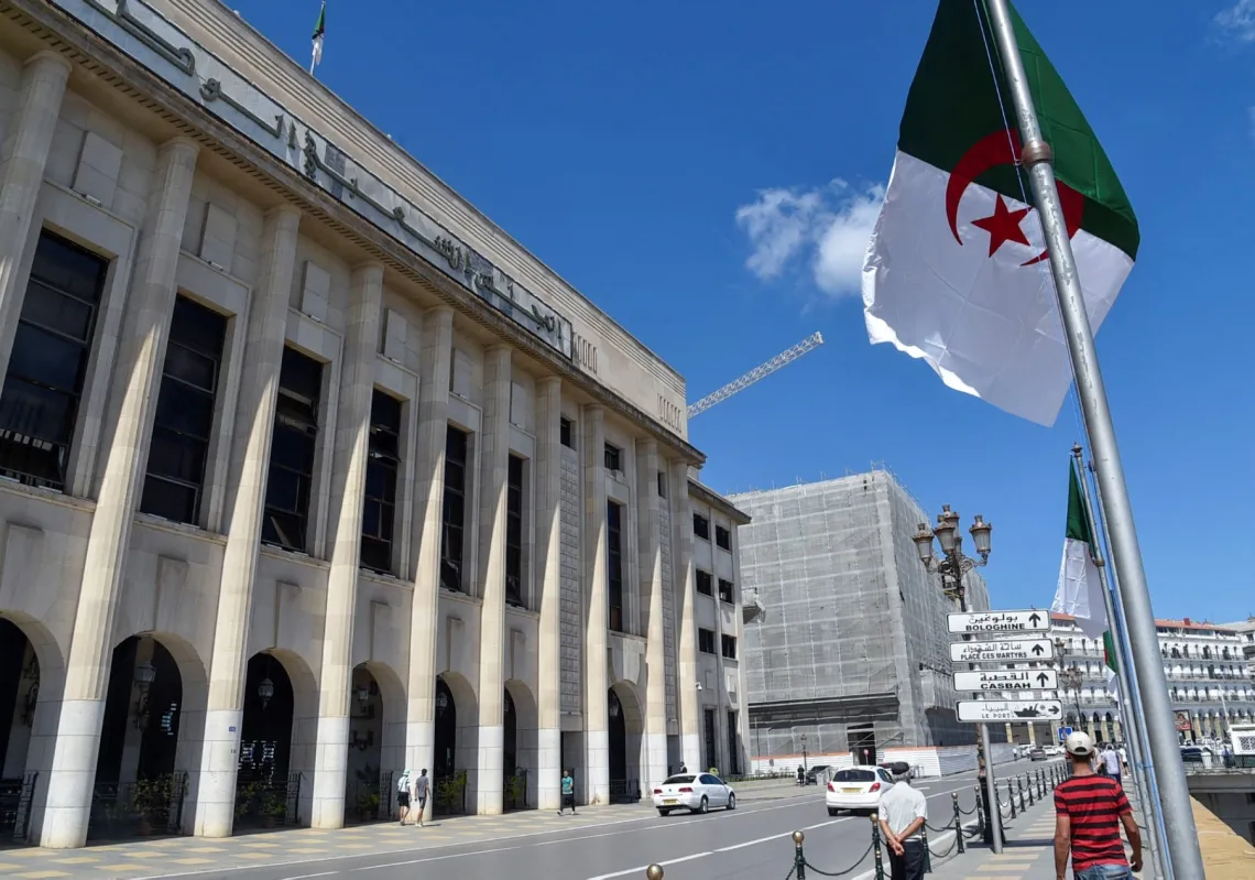 جزائريون يسيرون أمام مبنى المجلس الشعبي الوطني (البرلمان) خلال جلسة تصويت على الإصلاحات الدستورية في العاصمة الجزائر، في 10 سبتمبر 2020