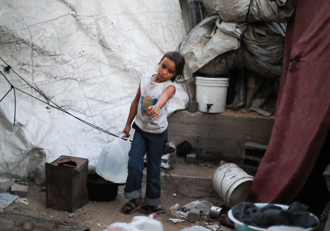 A Palestinian girl carries a container of water at a makeshift tent camp on the premises of the Islamic University in Gaza City, on 3 October 2026. 