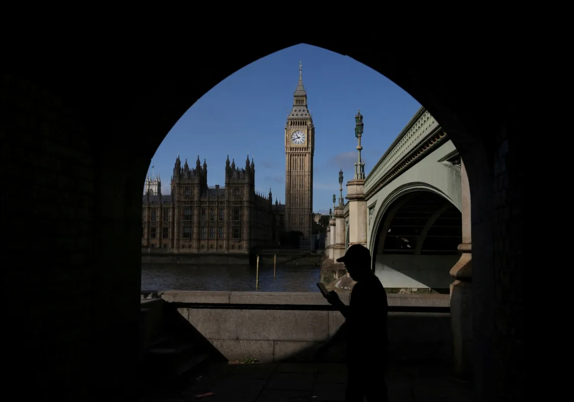A man looks at his phone in view of the Palace of Westminster in London, Britain, on 22 September 2023. 