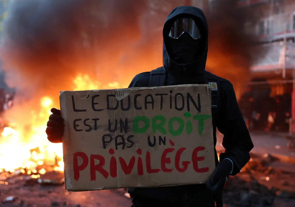 A masked protester holds a placard reading "Education is a right, not a privilege" as part of nationwide protests called by the "Yellow Vests" movement demanding better school conditions in France on 17 October 2026.   