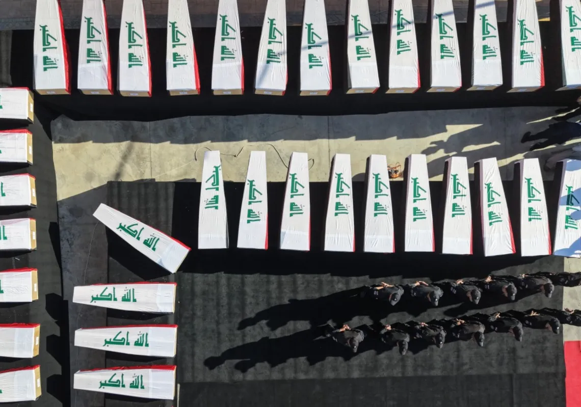 Security forces stand next to coffins lined up during the funeral ceremony of 47 victims killed by the Islamic State (IS) group during its capture of the city of Mosul in 2014, and whose remains were later found on 20 October 2026.