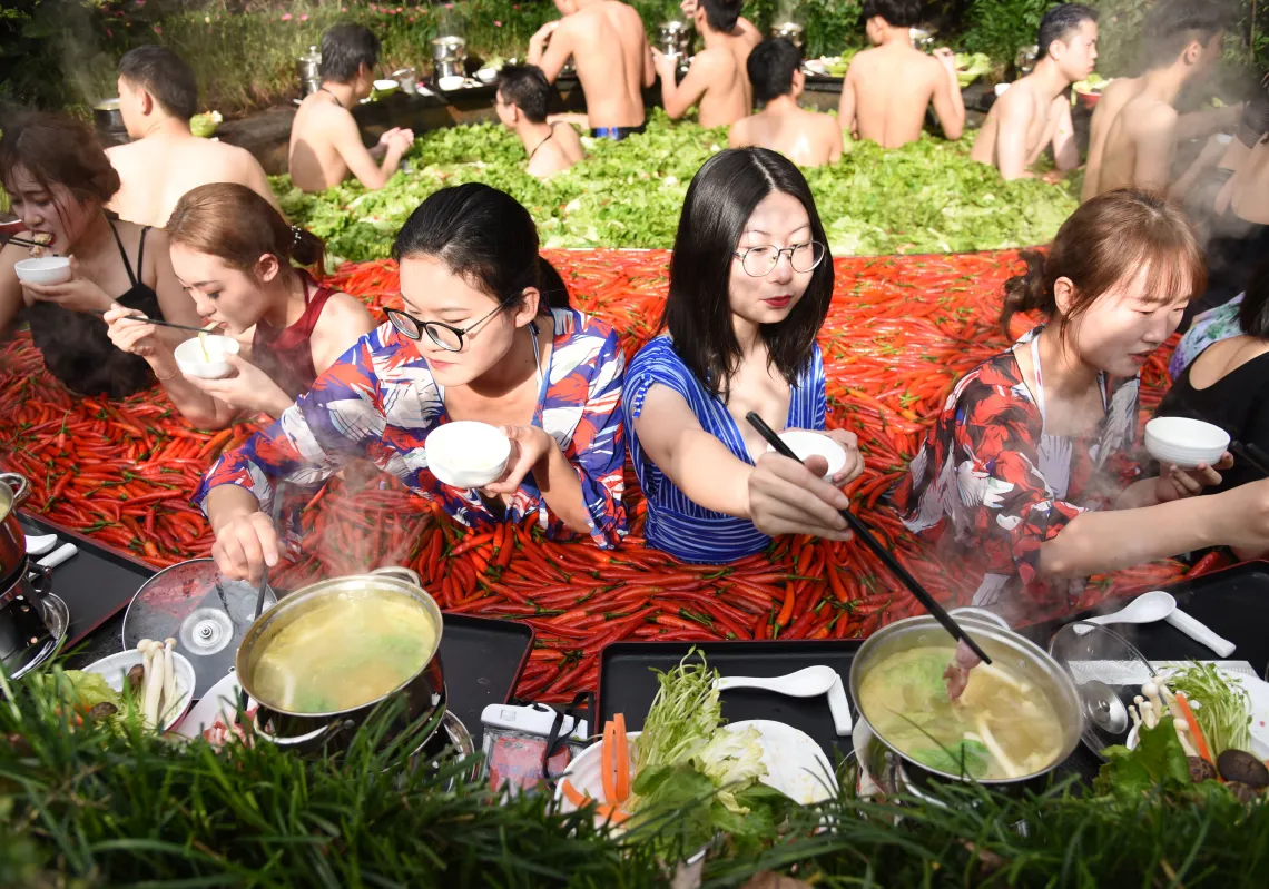 Citizens eat hot pot in a hot spring, which is shaped like a giant hot pot and filled with red chilies and lettuce, at a hotel on December 16, 2018 in Hangzhou, Zhejiang Province of China. (Getty)