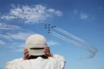 A boy covers his ears with his hands as the South Korean Air Force Black Eagles aerobatic team performs during the Seoul International Aerospace & Defence Exhibition (ADEX) in Seongnam, South Korea, October 17, 2025.  REUTERS/Kim Hong-Ji